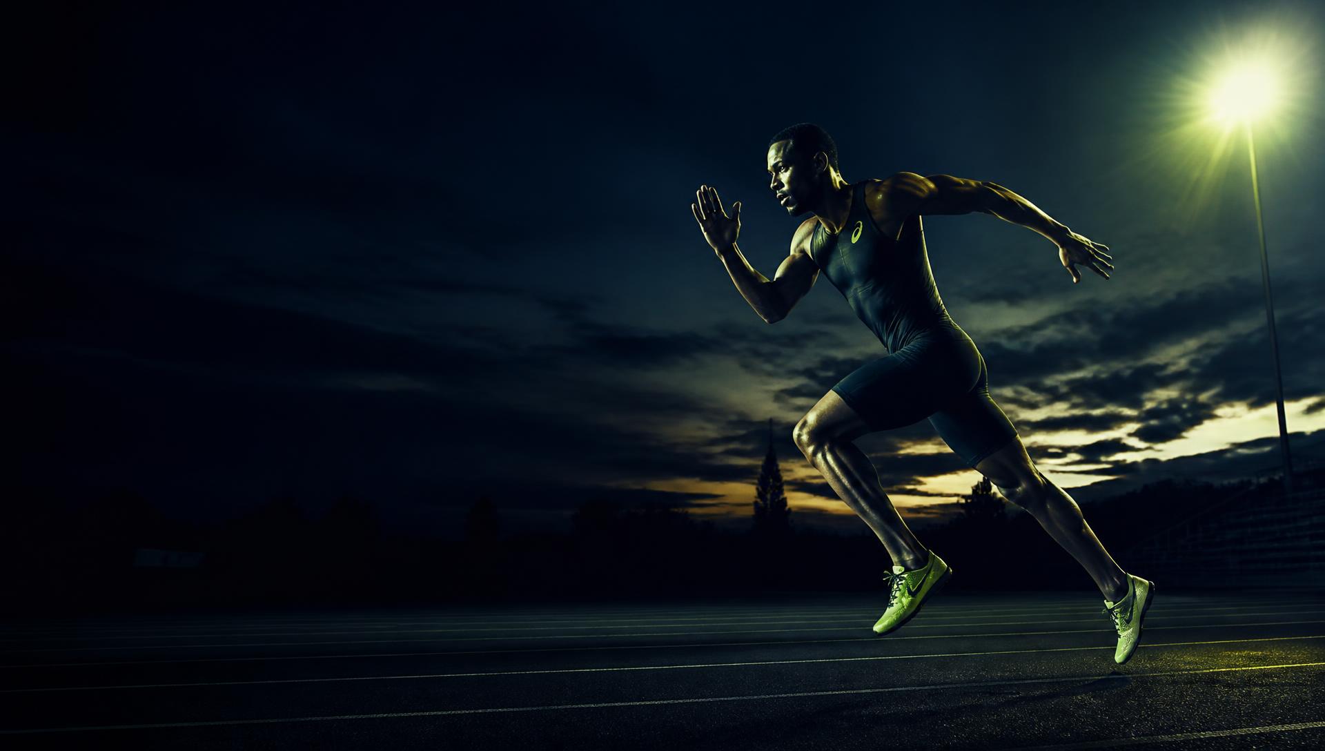 Sprinter accelerating on a floodlit running track at dusk